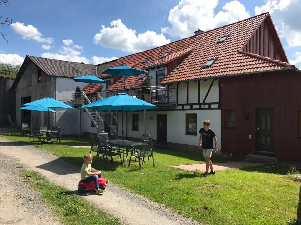 a woman and a child sitting in the yard of a house at Ferienwohnungen Elsbacher Hof in Erbach