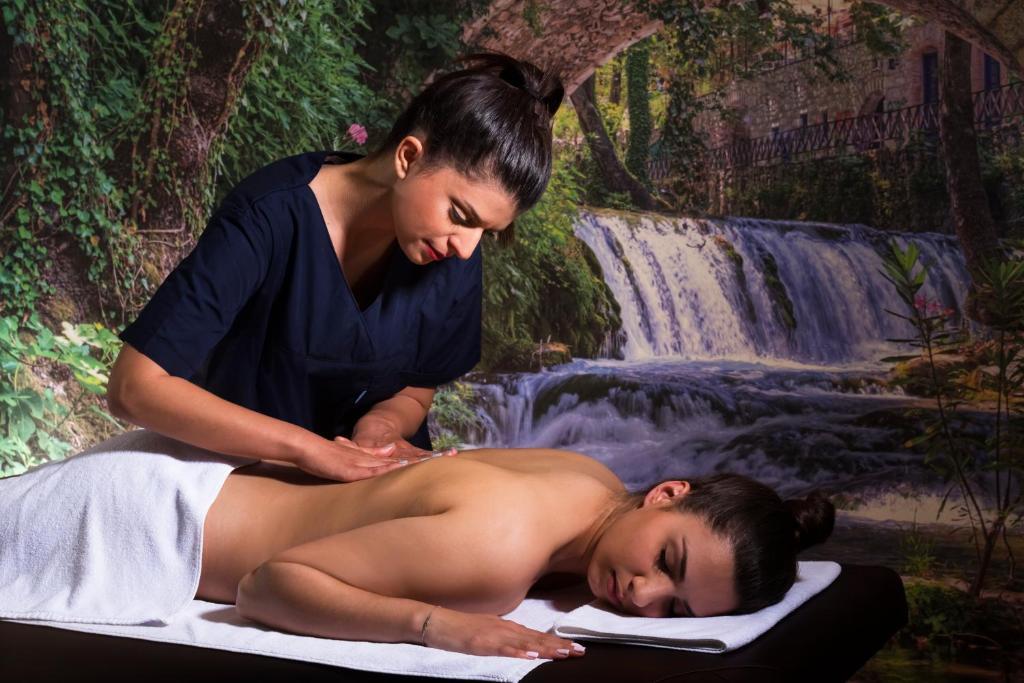 a woman getting a massage from a woman laying on a towel at Elite City Resort in Kalamata