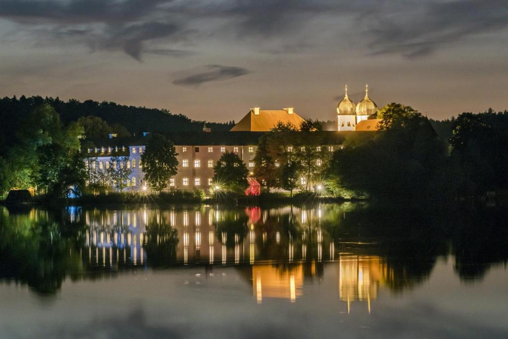 ein Gebäude am Ufer eines Sees in der Nacht in der Unterkunft Kloster Seeon in Seeon-Seebruck