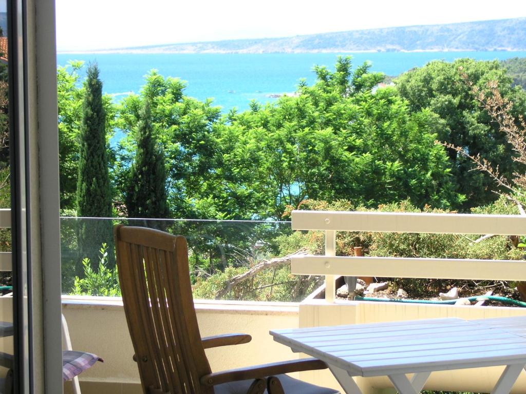 a table and chair on a balcony with a view of the ocean at Apartman Kucer in Krk