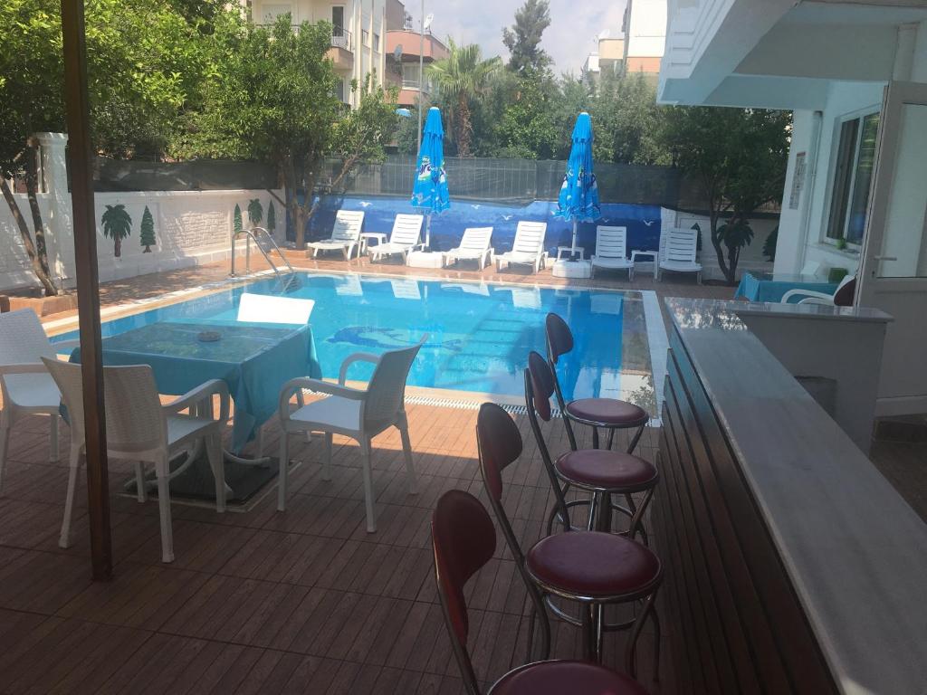 una piscina con sillas, una mesa y una mesa en Konyaaltı HOTEL, en Antalya