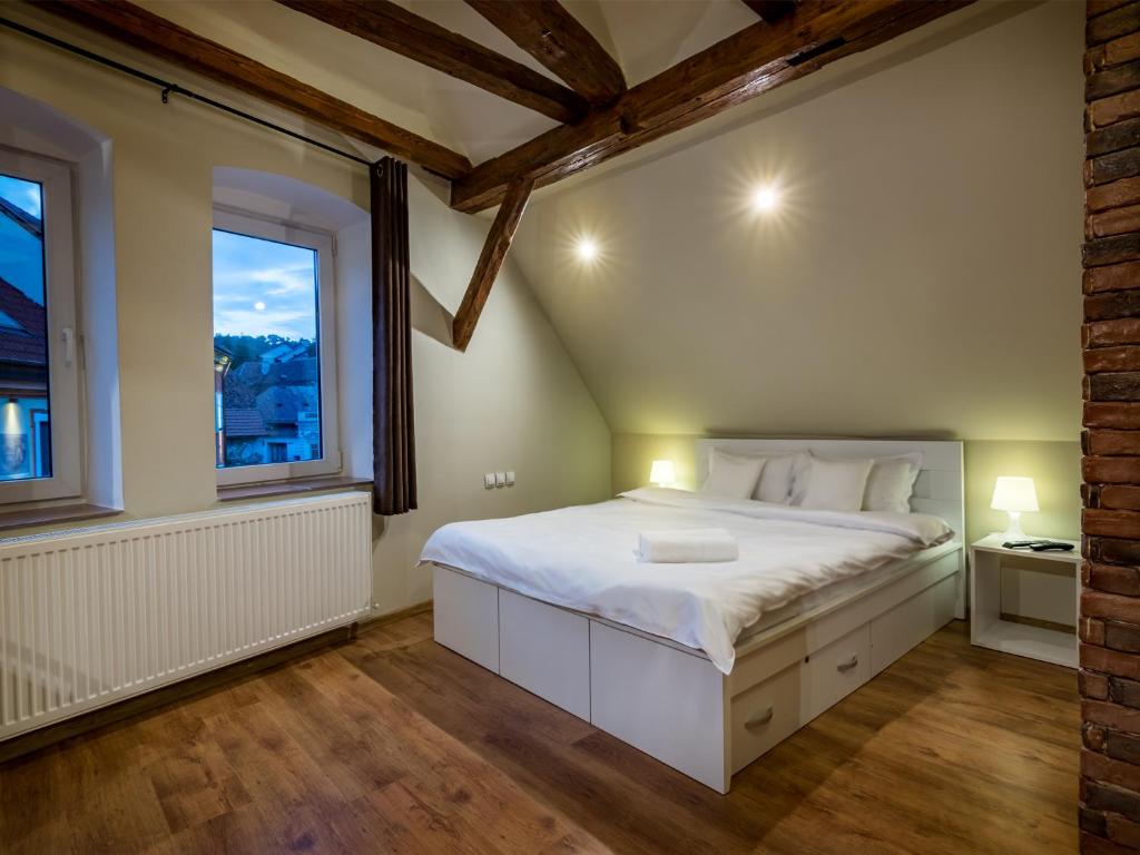 a bedroom with a white bed and two windows at Studio Unseen Brasov in Braşov
