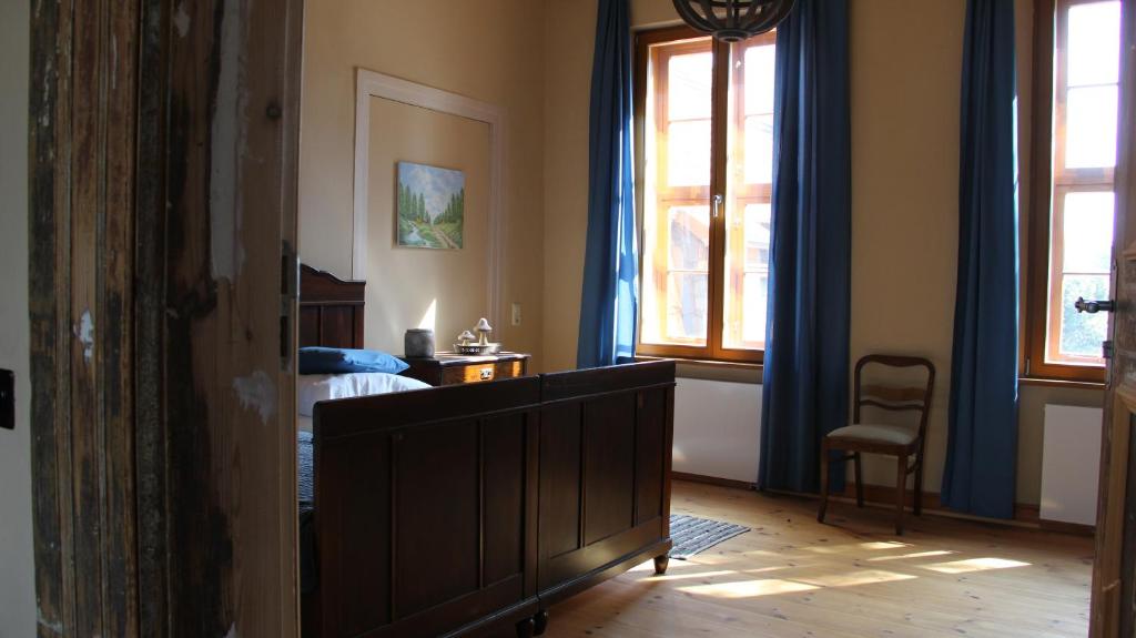 a bedroom with a bed and a chair and windows at Lindstedter Gutsstuben in Gardelegen