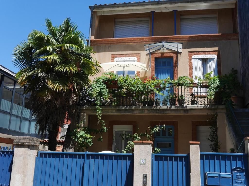 un bâtiment avec une clôture bleue et un palmier dans l'établissement Les Loges des Chalets, à Toulouse