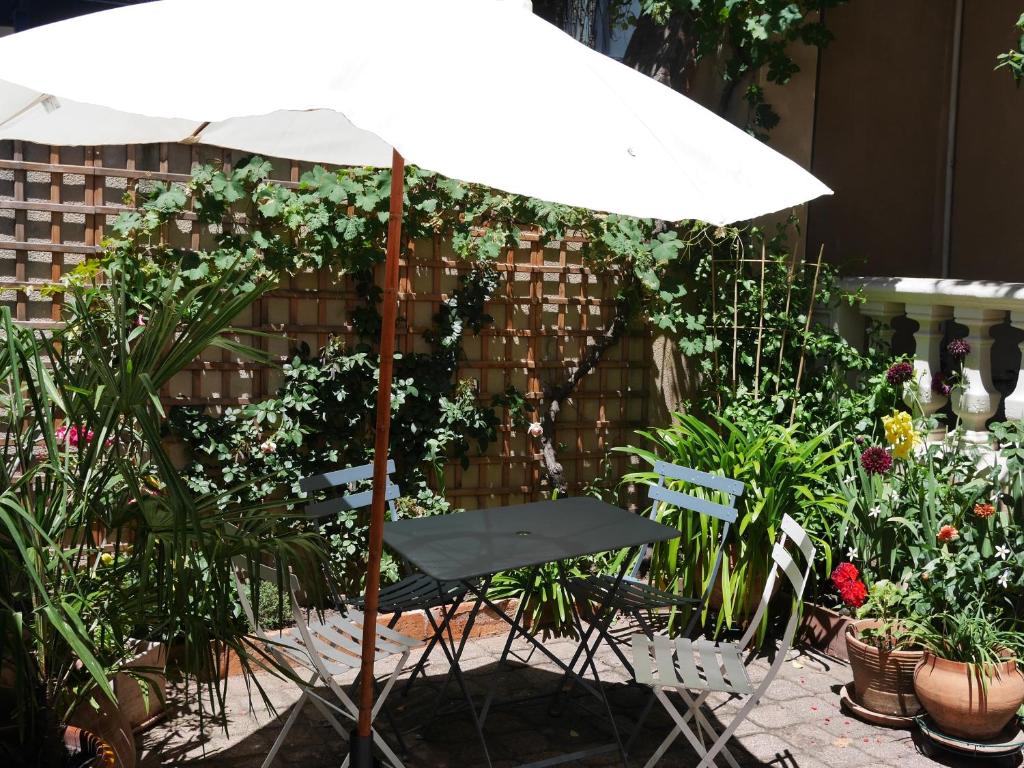 a white umbrella sitting in a garden with plants at Les Loges des Chalets in Toulouse