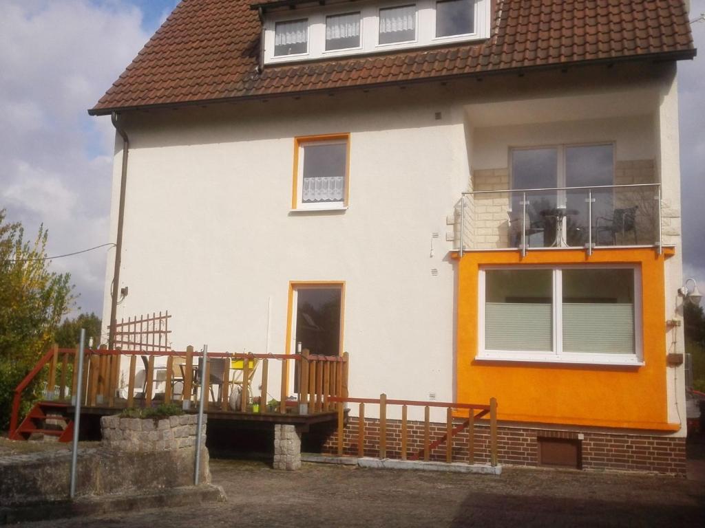 ein weißes und orangefarbenes Haus mit einem Balkon in der Unterkunft Ferienwohnung Ruhepol in Vellmar