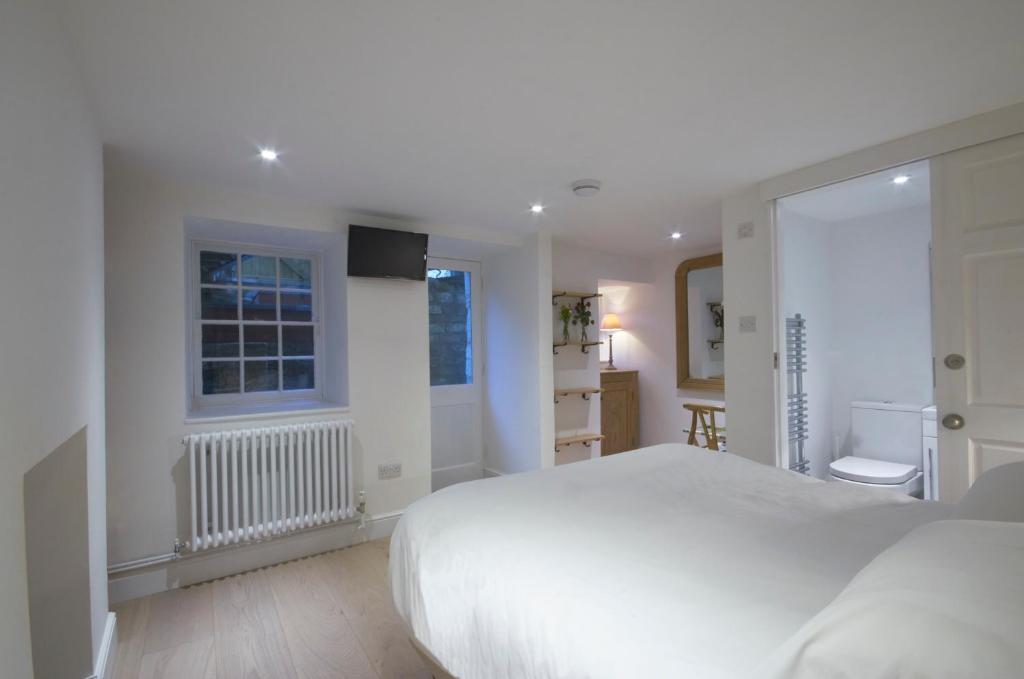una camera bianca con un letto bianco e una finestra di The Secret Escape a Bath