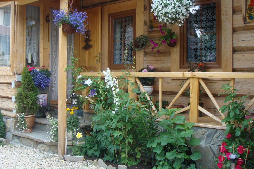 una casa de madera con flores delante en Pokoje u Ziutki en Witów