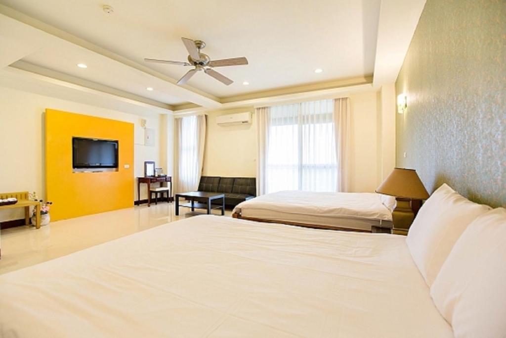 a hotel room with two beds and a flat screen tv at 百分百民宿 in Taitung City