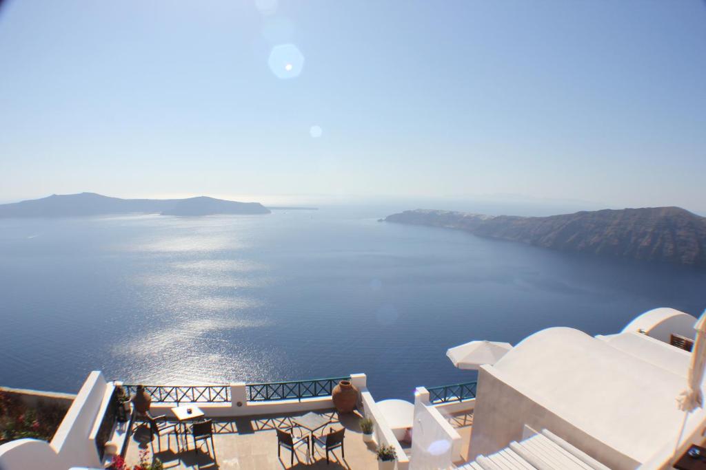 un balcone con tavoli e sedie e vista sull'oceano. di Afroessa Hotel by Pearl Hotel Collection a Imerovigli