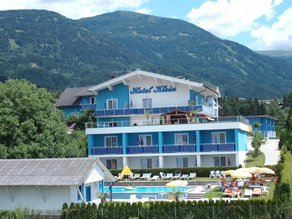 un edificio azul y blanco con piscina y complejo en Hotel Klein - Seebodenerhof, en Seeboden