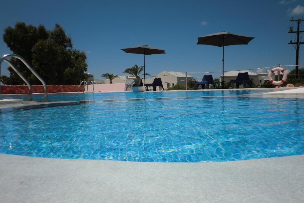 ein großer Pool mit blauem Wasser und Sonnenschirmen in der Unterkunft Poseidon Suites Hotel in Stavros