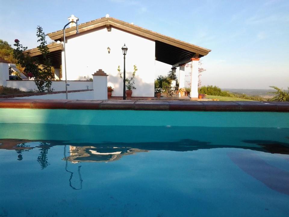 uma piscina de água em frente a uma casa em Las Cañadillas em El Castillo de las Guardas