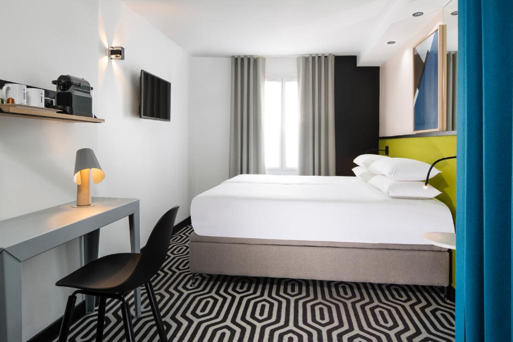 パリにあるホテル ピリムのベッドとデスクが備わるホテルルームです。