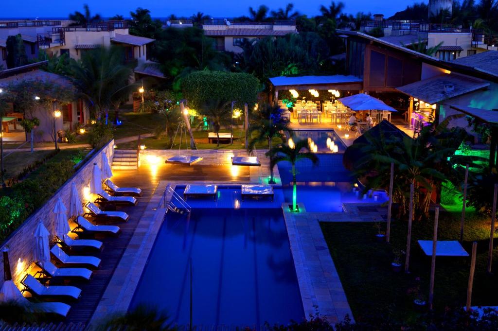 una piscina por la noche con tumbonas y mesas en A15 Apt particular no condomínio Pipa Beleza, en Pipa