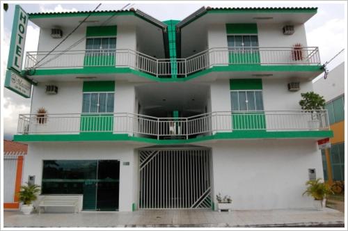 a tall white building with green trim at Hotel Master in Primavera do Leste