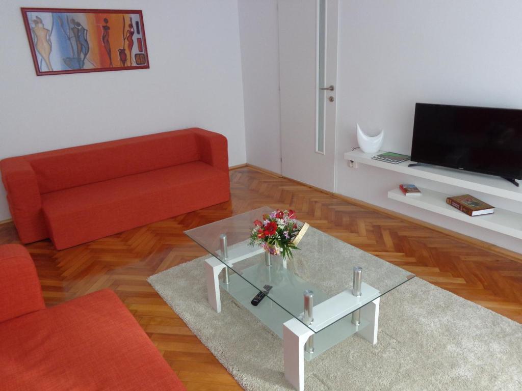 アルバ・ユリアにあるOlympus Apartmentのリビングルーム(赤いソファ、ガラスのコーヒーテーブル付)