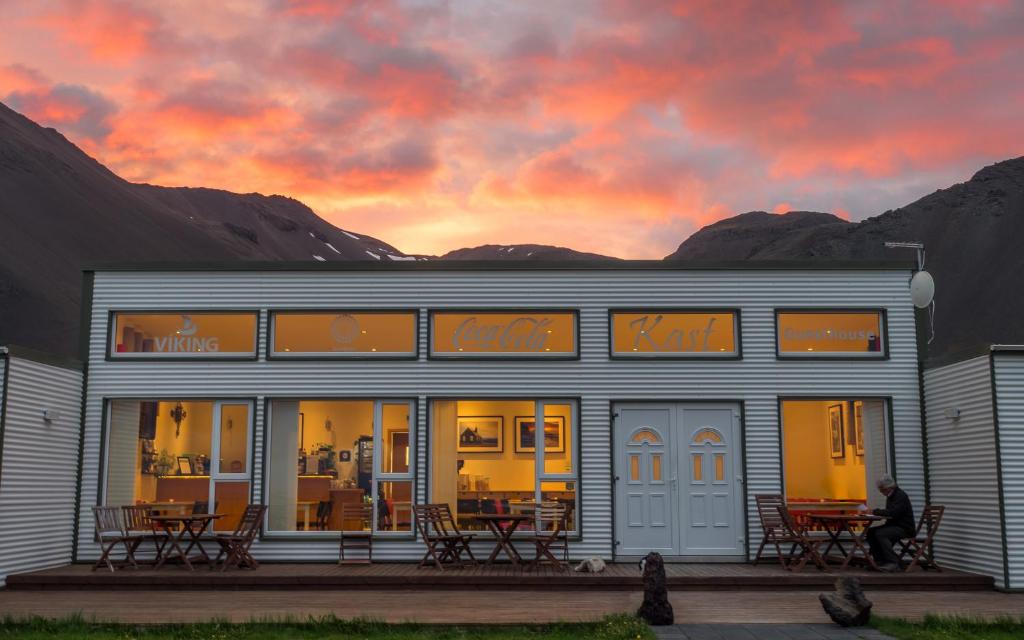 ein Gebäude mit Tischen und Stühlen vor einem Sonnenuntergang in der Unterkunft Kast Guesthouse in Lysudalur