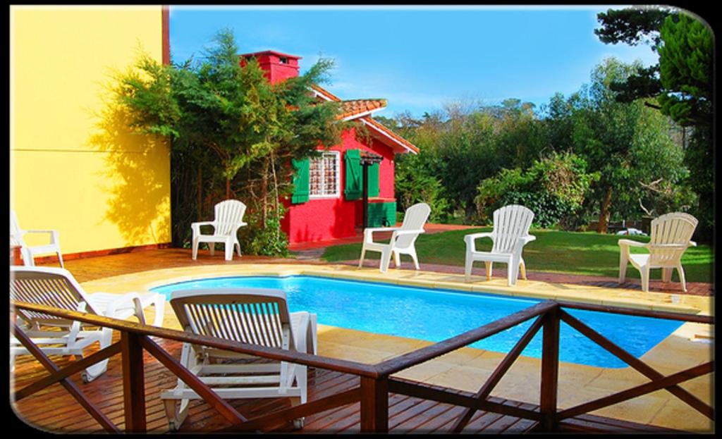 un grupo de sillas sentadas alrededor de una piscina en Villa Olimpia Cabañas en Villa Gesell