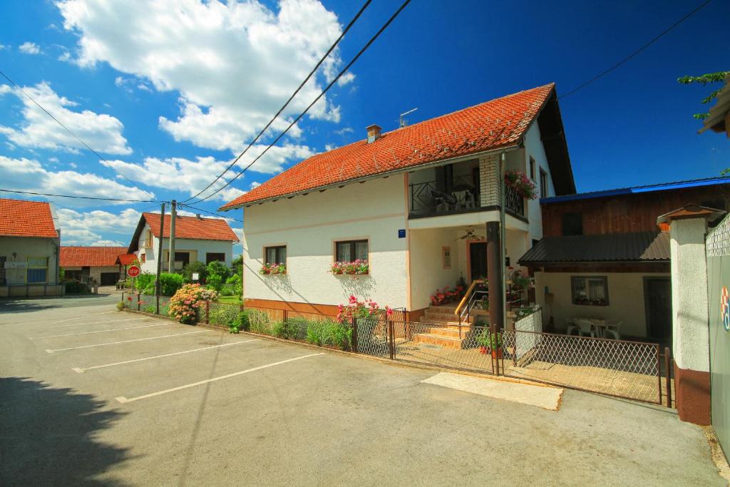 Biały dom z pomarańczowym dachem i parkingiem w obiekcie Apartman Josipa w mieście Drežnik Grad