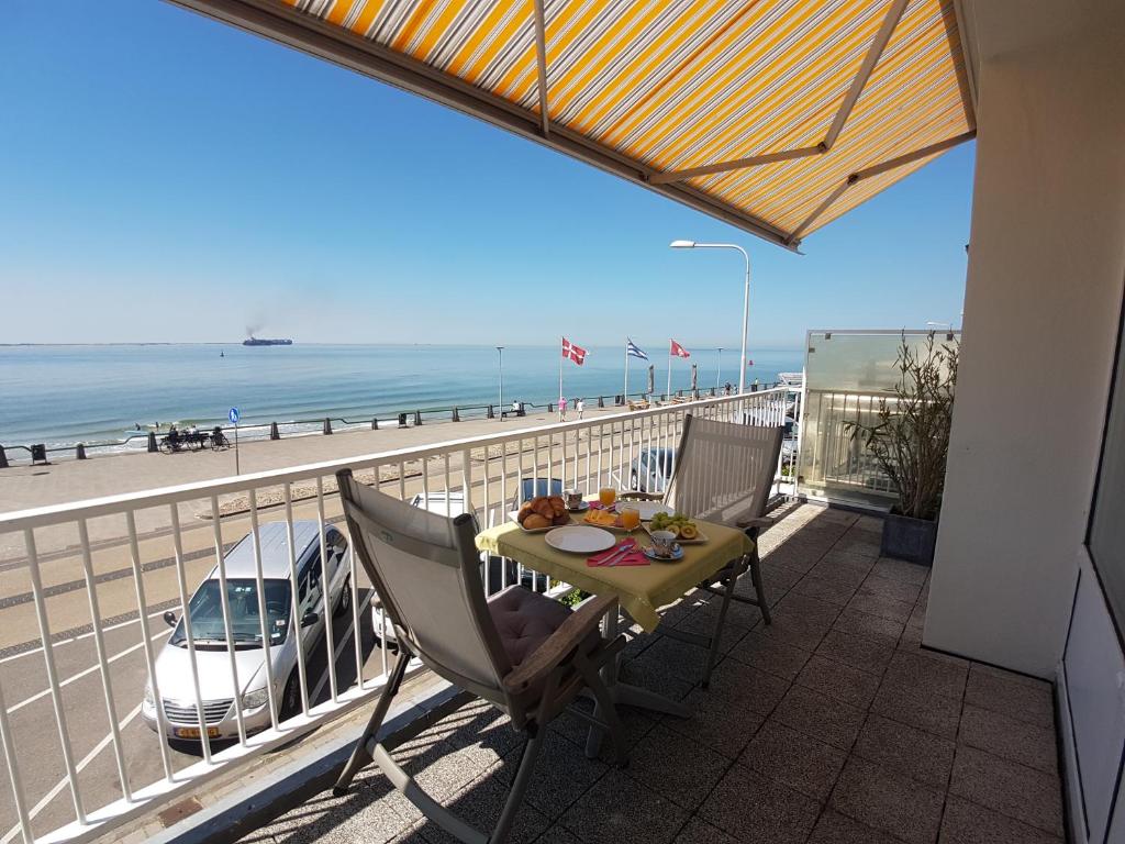 einen Tisch und Stühle auf einem Balkon mit Blick auf den Strand in der Unterkunft APARTMENT BY THE SEA Bed by the Sea in Vlissingen