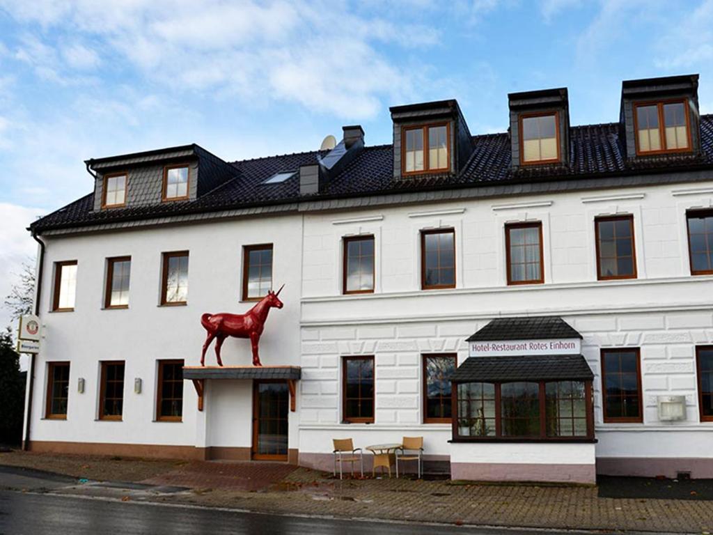 ein großes weißes Gebäude mit einer Pferdestatue darauf. in der Unterkunft Hotel-Restaurant Rotes Einhorn Düren *** Superior in Düren - Eifel