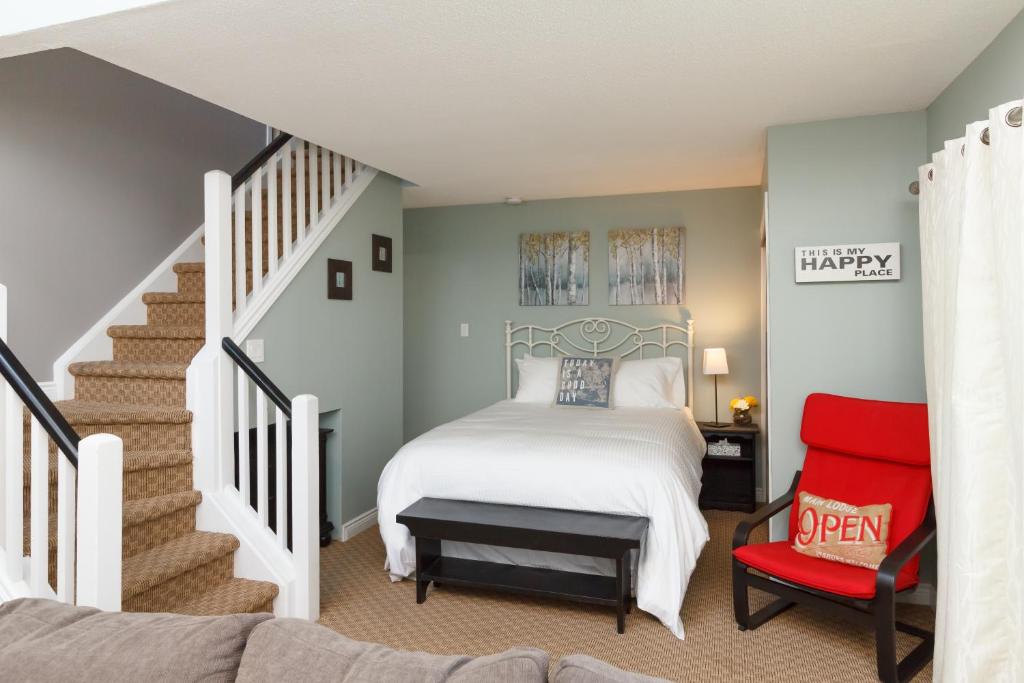 a bedroom with a bed and a staircase with a red chair at Mountain Side Condo Loft at The Blue Mountains in Blue Mountains