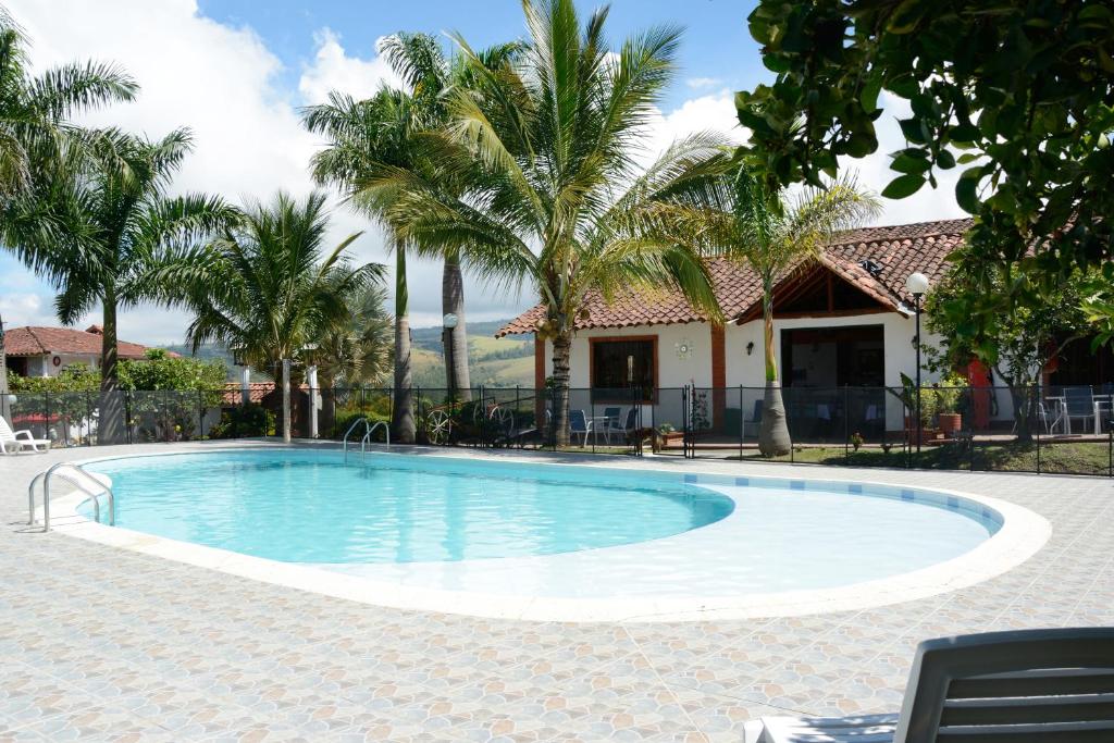 una piscina con palmeras y una casa en Hotel Campestre la Loma curiti, en Curití