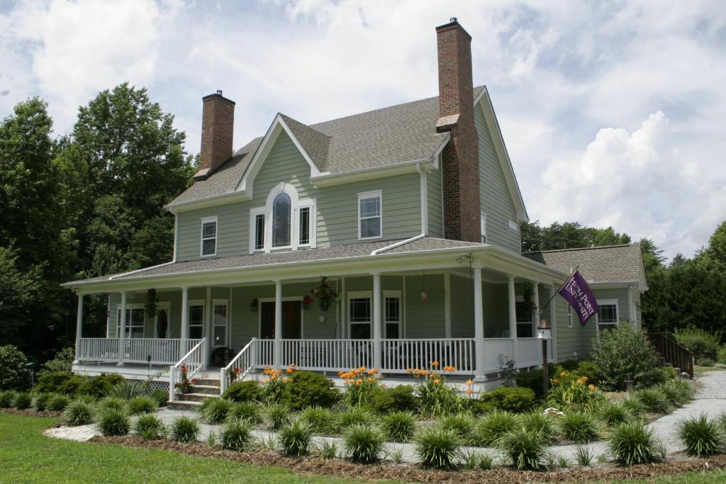 a green house with a porch and flowers at Seven Oaks Inn Bed and Breakfast in High Point