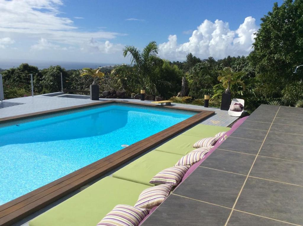 une piscine avec des chaises longues et une piscine dans l'établissement Bungalow Premium Tahiti, à Punaauia