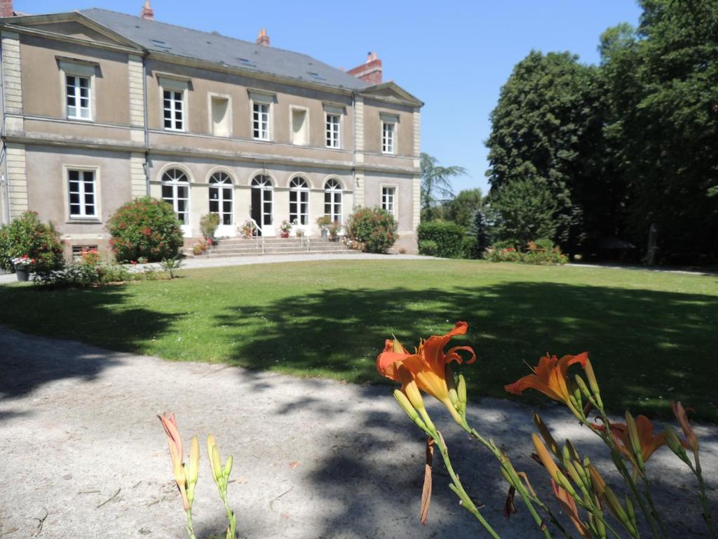 een groot huis met oranje bloemen ervoor bij Domaine du Plessis Grimaud in Saint-Viaud