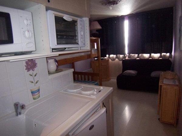 a kitchen and living room with a microwave and a couch at vostok G173 in Le Corbier