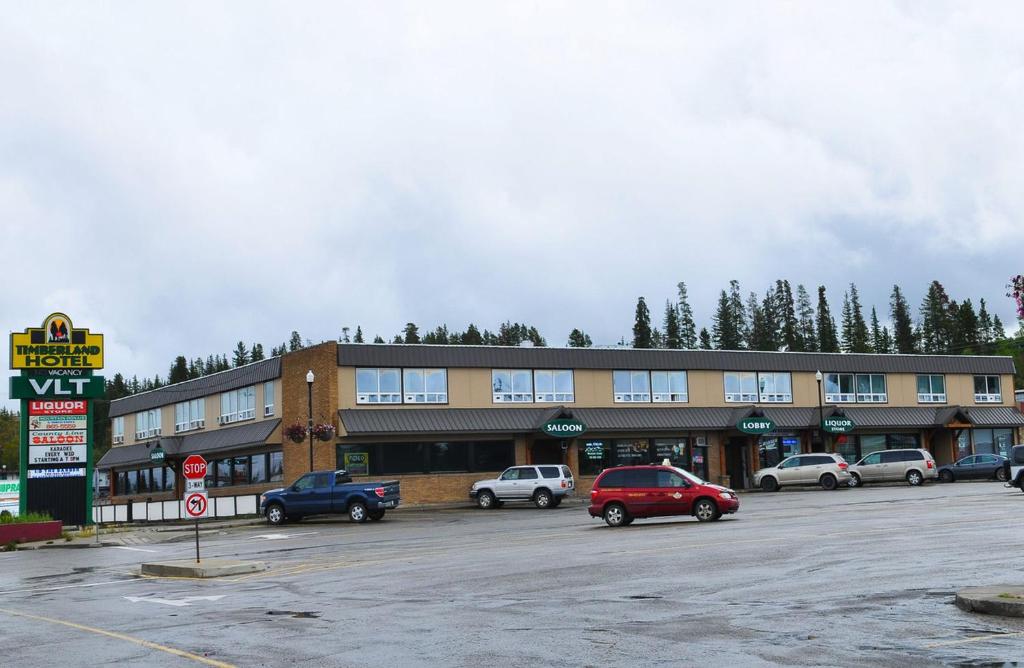 a large building with cars parked in a parking lot at Timberland Hotel in Hinton