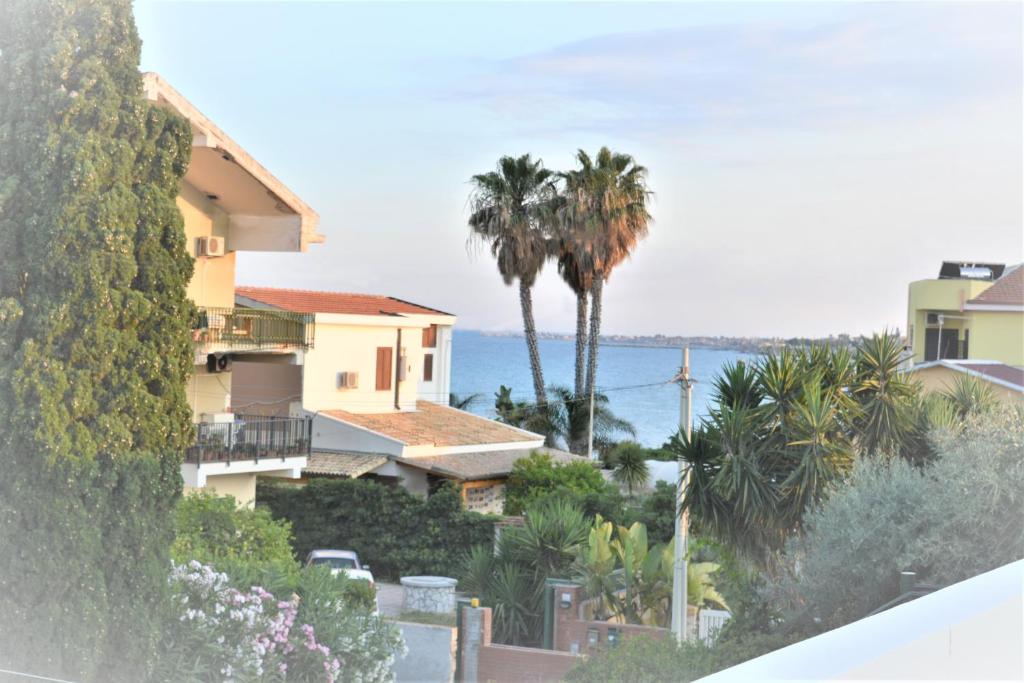 a view of a house with palm trees and the ocean at Villa ANNY in Avola