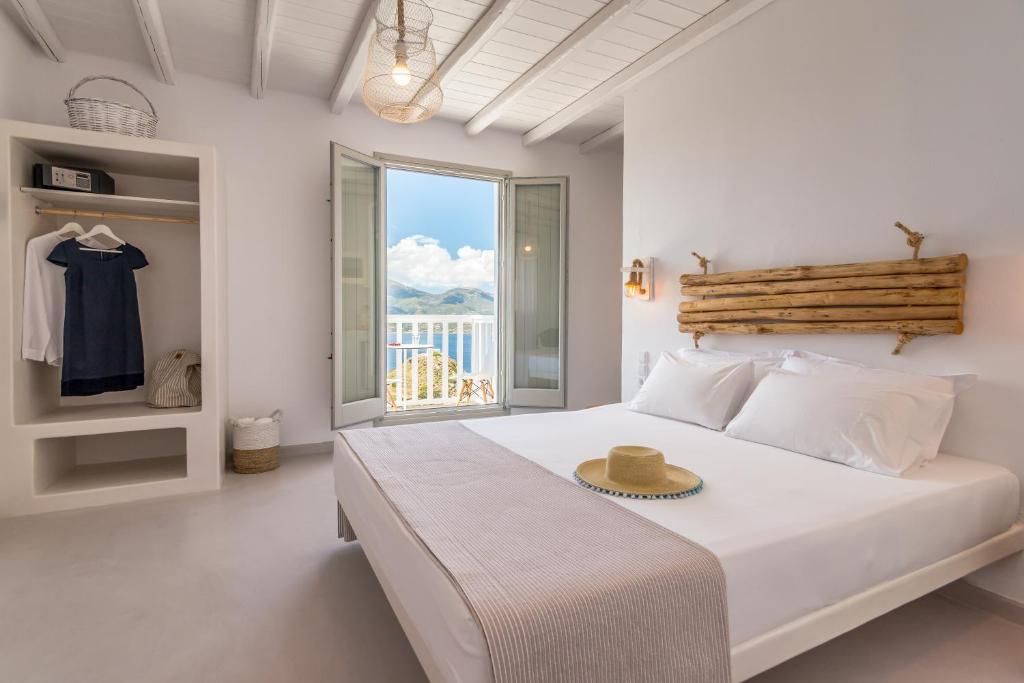 a white bedroom with a bed with a hat on it at Halara Studios in Plaka Milou