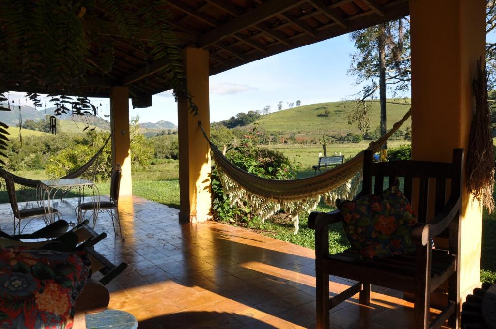 a porch with hammocks and a view of a field at Pousada Casa Da Fazenda in Paraisópolis