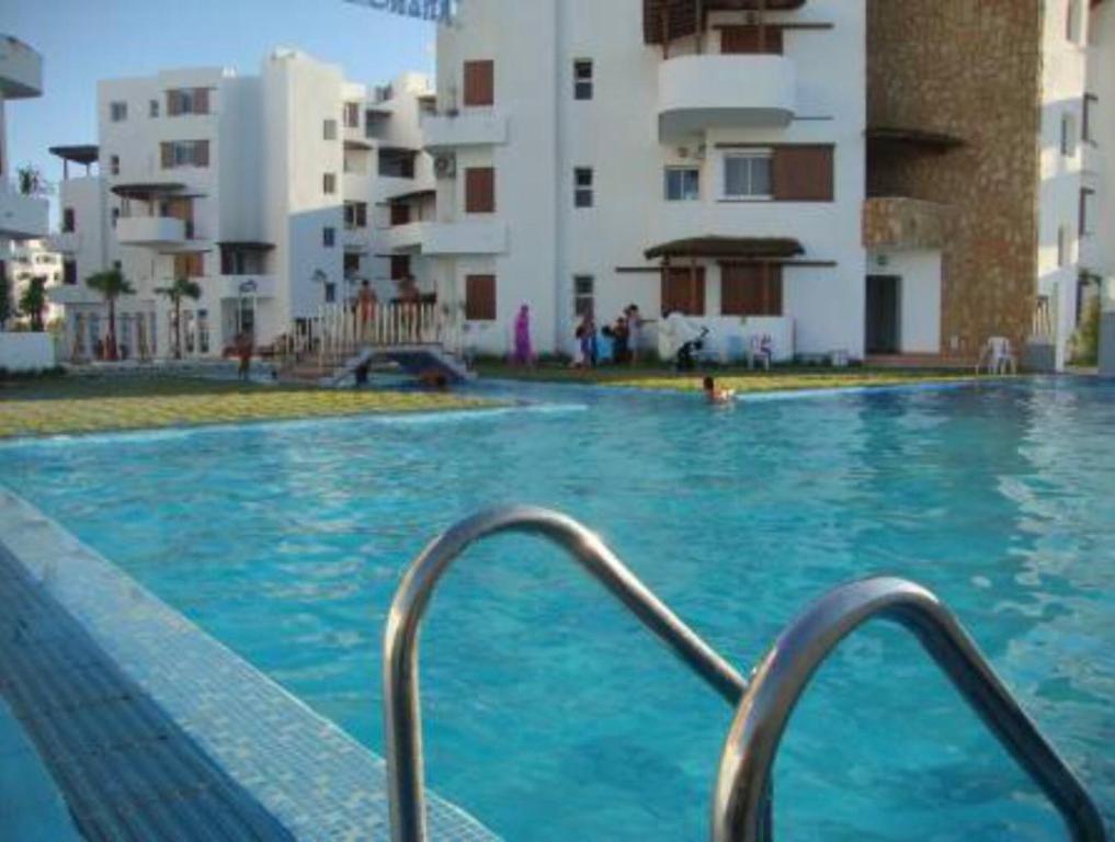 - une piscine d'eau bleue en face des bâtiments dans l'établissement Dunes of Martil families only, à Martil