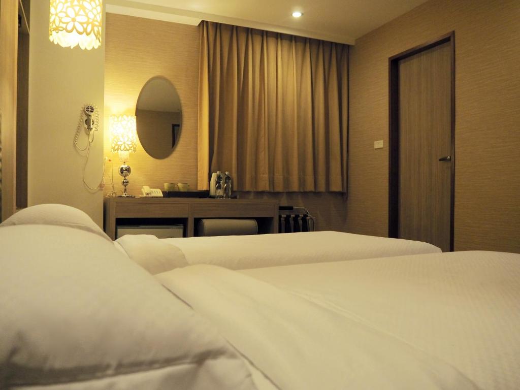 a hotel room with two beds and a mirror at The Riverside Hotel Hengchun in Hengchun South Gate