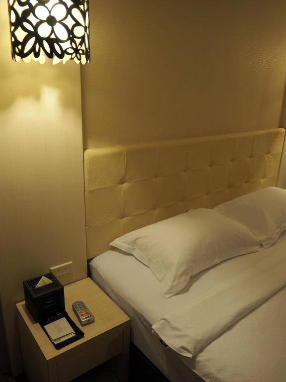 a bedroom with a bed and a nightstand with a bed sidx sidx at The Riverside Hotel Hengchun in Hengchun South Gate