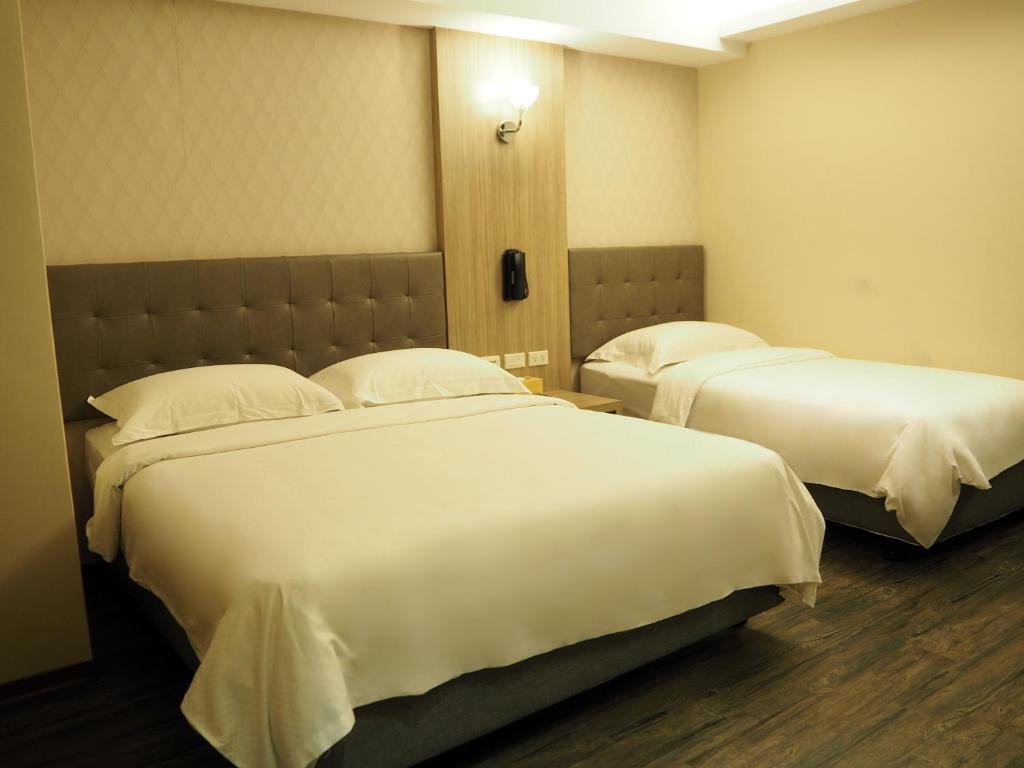 two beds in a hotel room with white sheets and pillows at The Riverside Hotel International in Kaohsiung