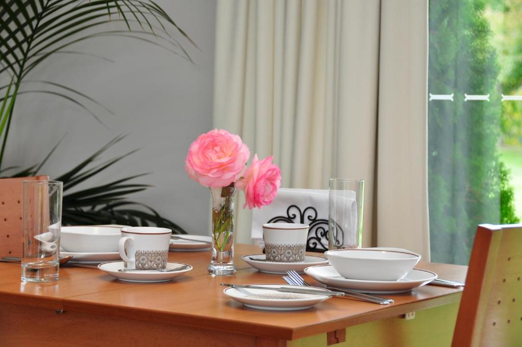 einen Holztisch mit Platten und eine Vase mit einer rosa Blume in der Unterkunft Clifton Gardens Bed & Breakfast - Orange in Orange