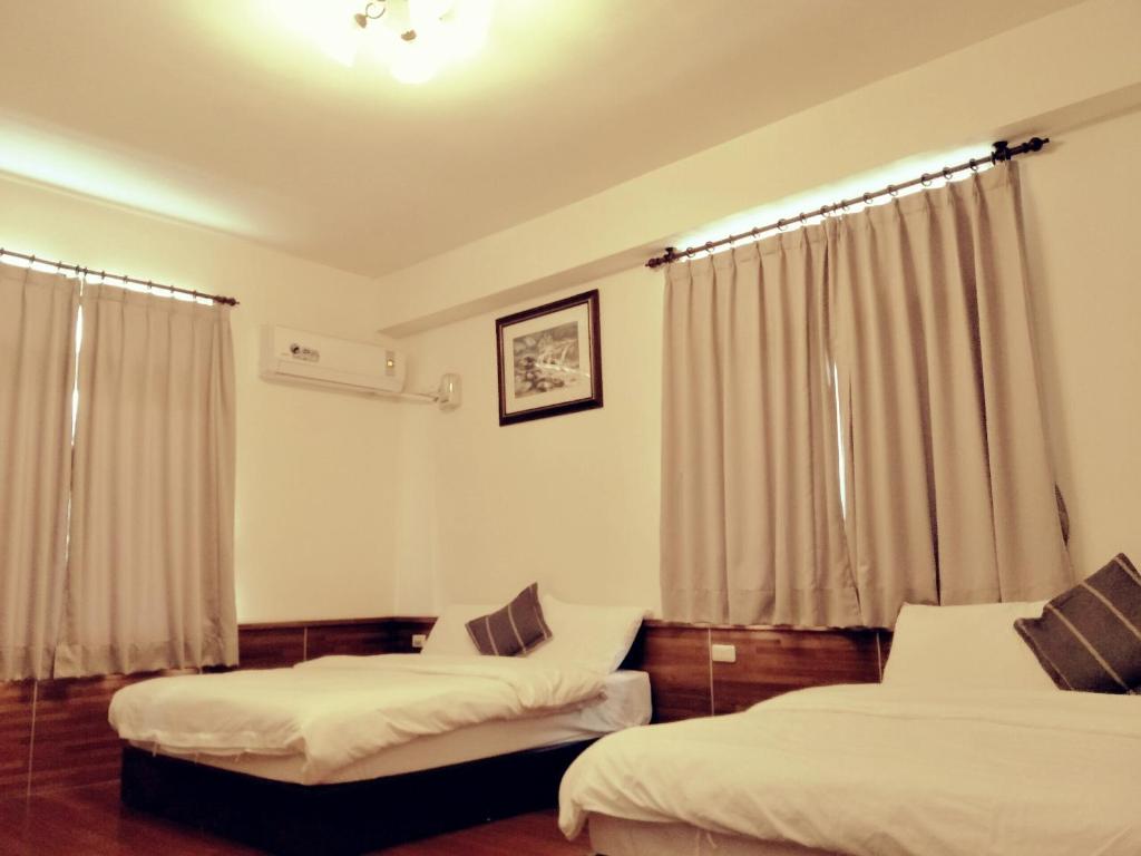 a hotel room with two beds and curtains at Lu He Feng Homestay in Luodong
