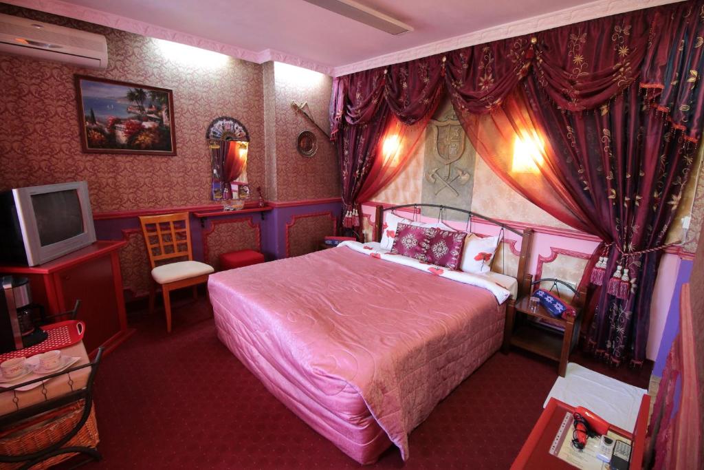 a bedroom with a pink bed and a television at Guest House Unika in Tryavna