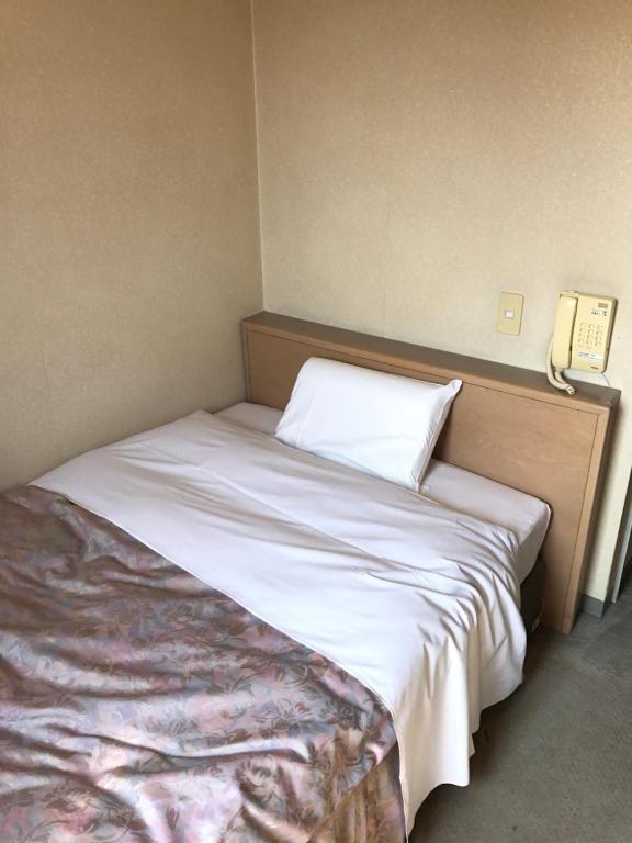a bed in a room with a phone on the wall at Hotel Muroran Hills in Muroran