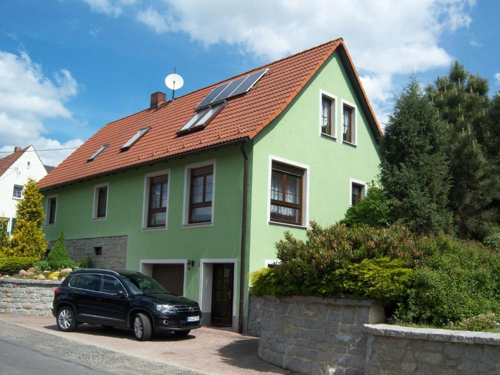 a green house with a car parked in front of it at Ferienwohnung "An der St. Ludmila" in Crostwitz