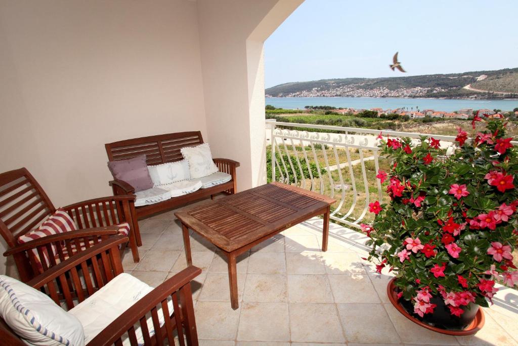 a balcony with a table and a couch and flowers at Apartman Dinka in Trogir