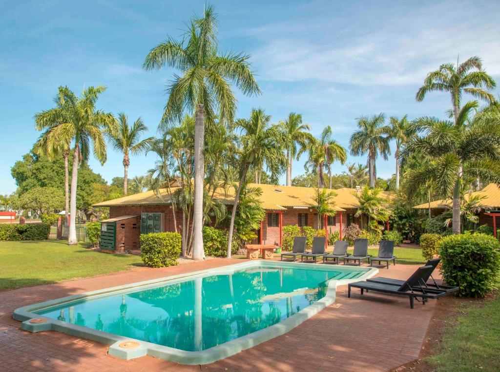 a house with a swimming pool and palm trees at Bayside Holiday Apartments in Broome