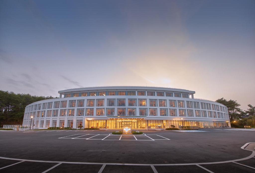 a large building in a parking lot at dusk at Naksan Beach Hotel in Yangyang