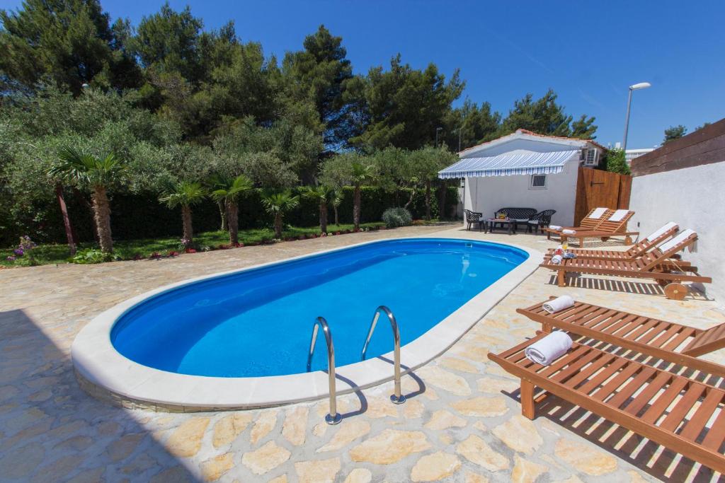 a swimming pool with two chairs and a building at Apartmani Mariva in Vodice