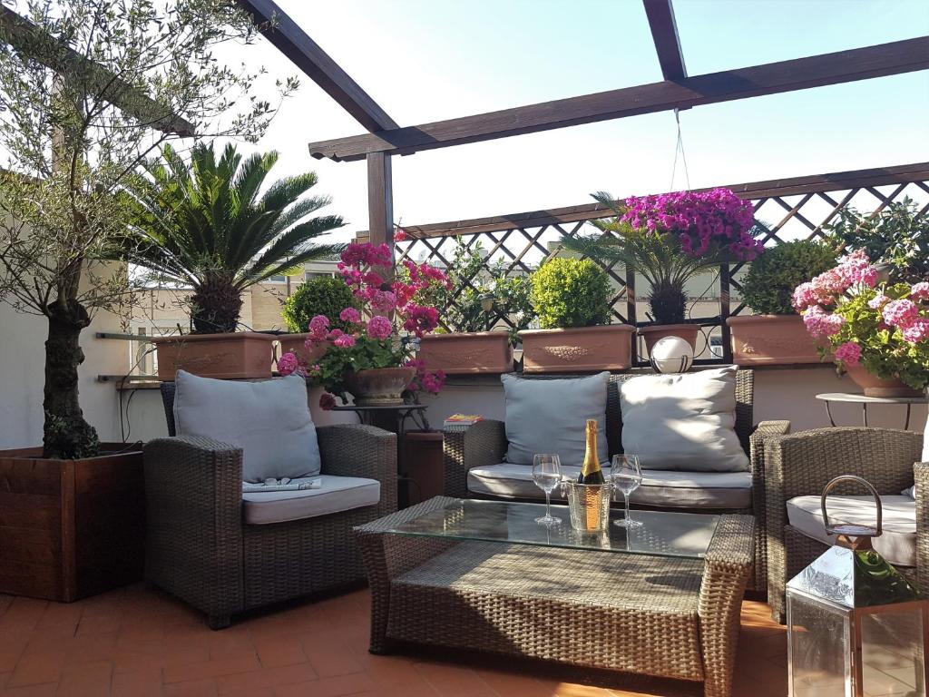 a patio with wicker chairs and tables and flowers at Althea Inn Roof Terrace in Rome